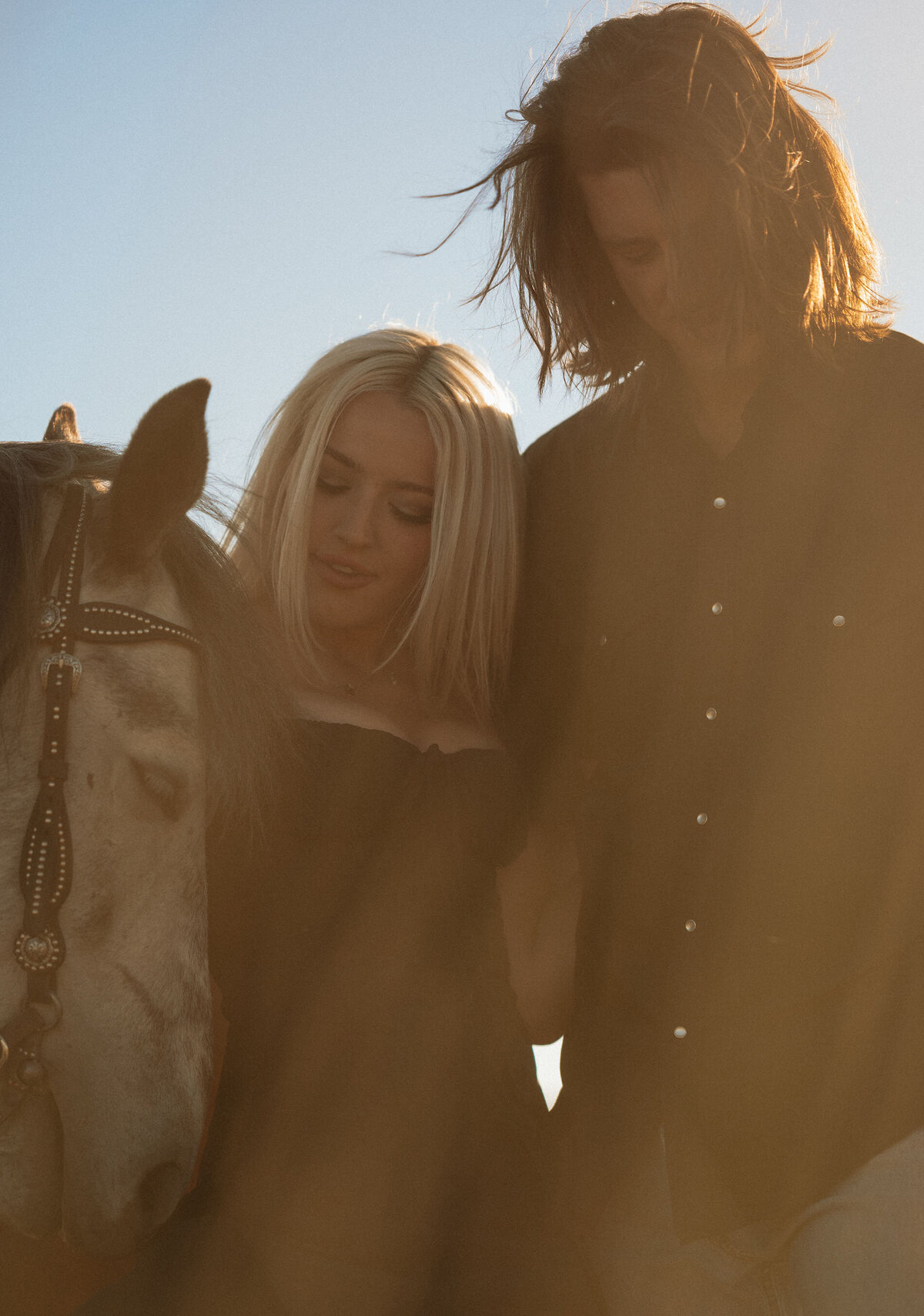 romantic photo of couple sharing a quiet moment with their horse as they enjoy the golden light