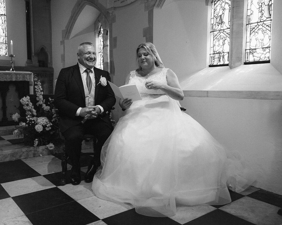 Sat in church a bride and groom laugh together after becoming husband and wife.