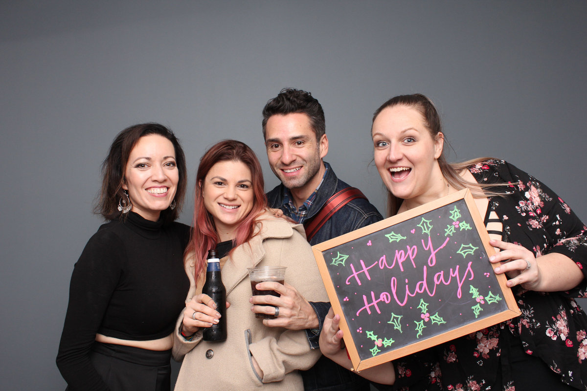 Employees party at a company holiday party with a photo booth rental