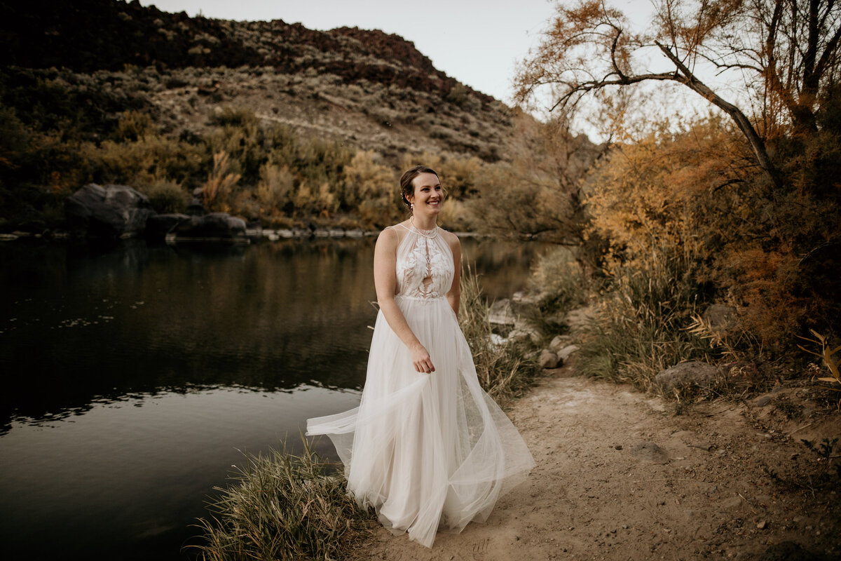 bride twirling dress by a river