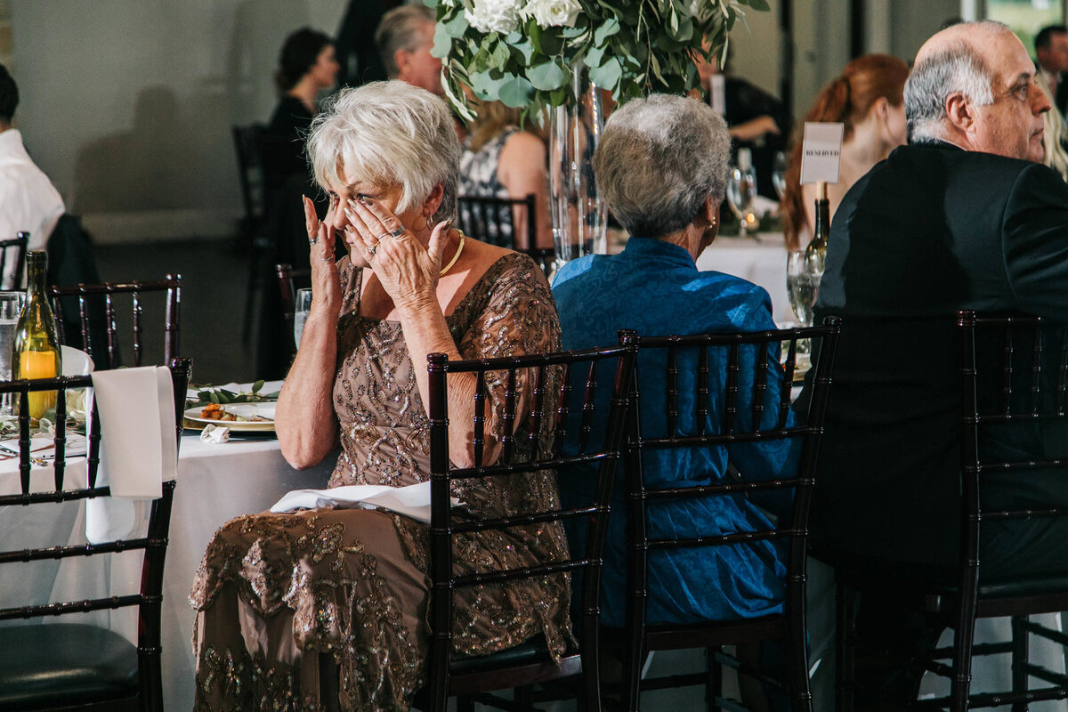 Candid moment during the wedding reception with the grandmother wiping away tears during a speech.
