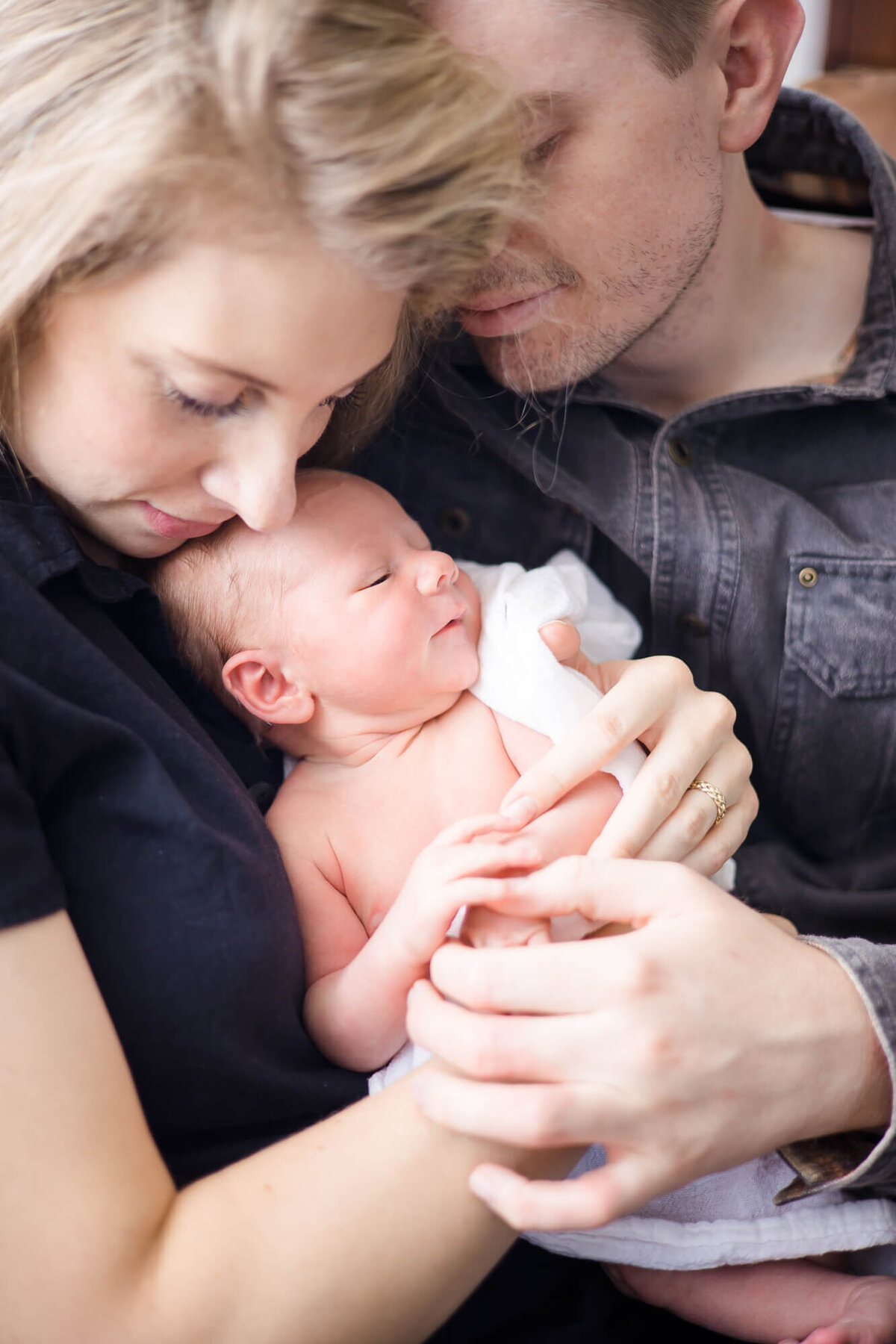 newborn baby boy content and cozy in his parents arms