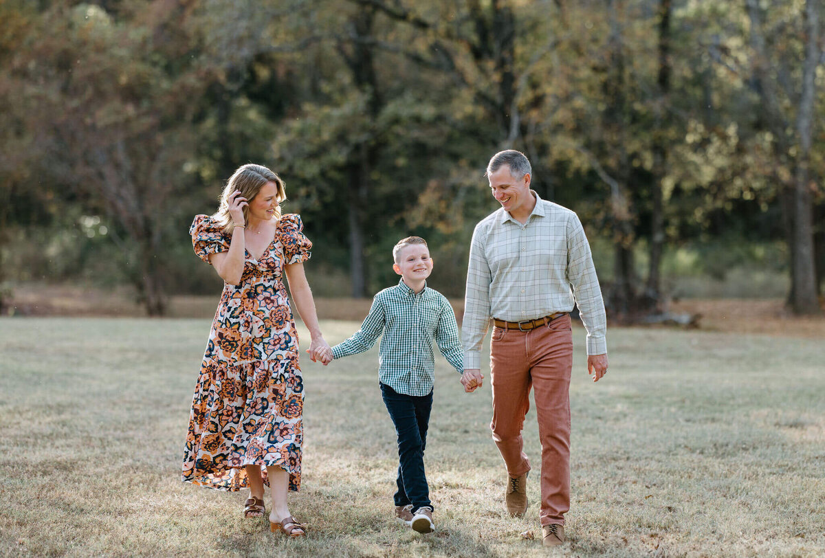 candid photo of family walking through field wearing fall colors during family pictures in Longview, TX
