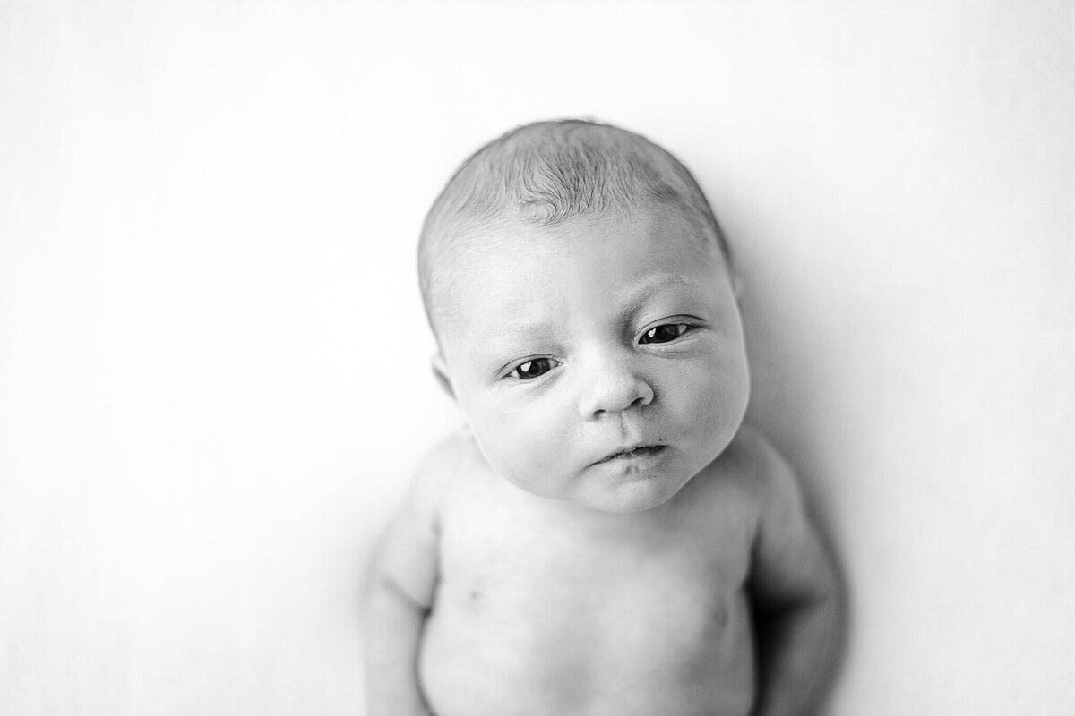 black and white image of baby lying looking at the camera