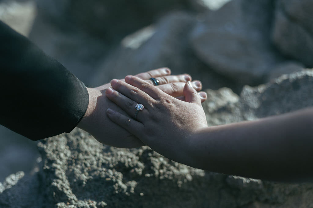 Two hands laid on top of each other showing off wedding rings.