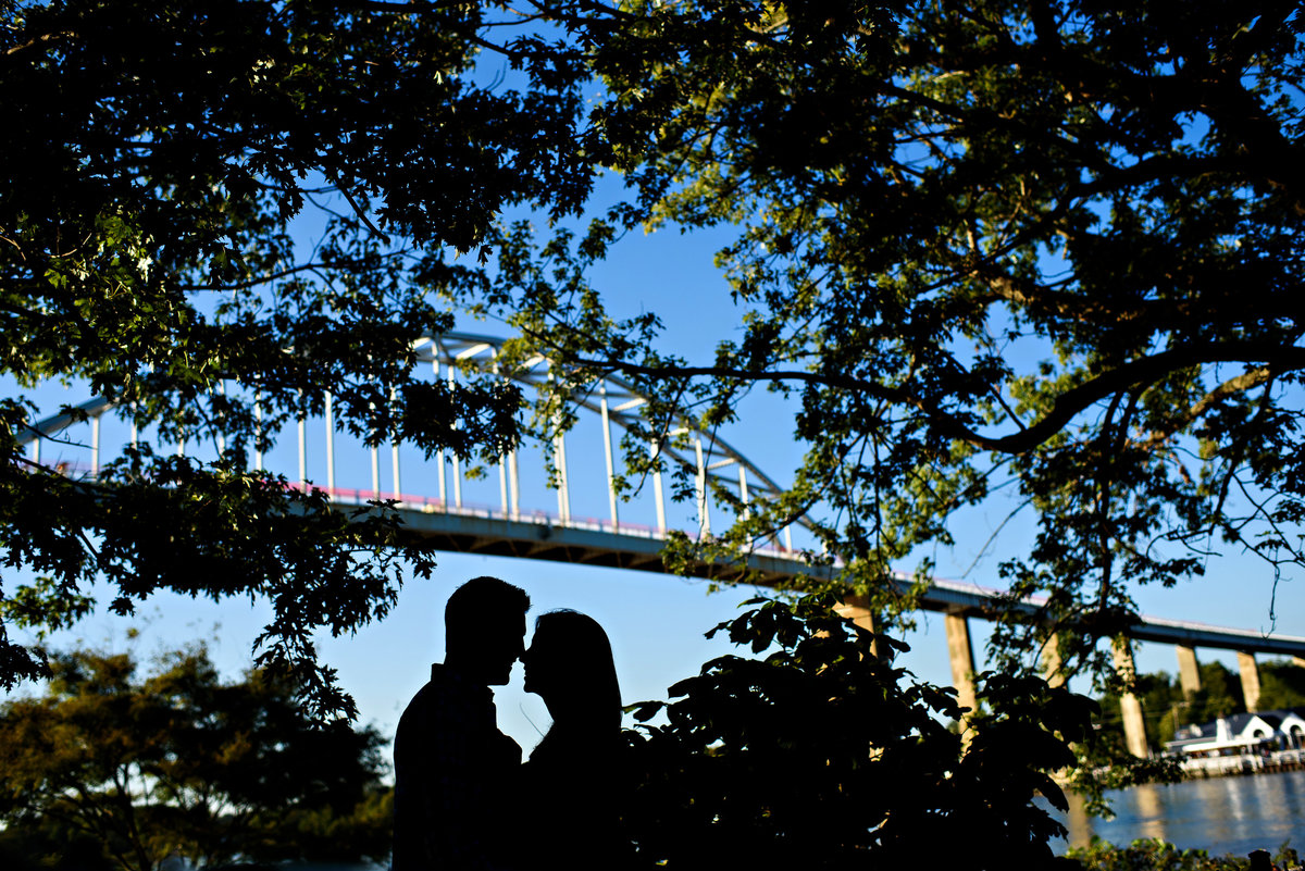 A silhouette of a couple under the Chesapeake bridge.