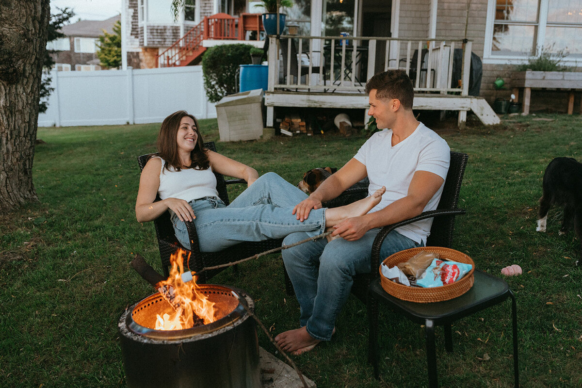 couple sitting in front of fire during engagement photos, captured by Elsie Goodman, an NYC engagement and couples photographer