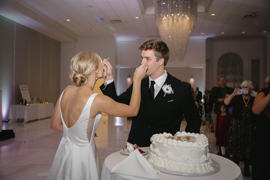 bride and groom feeding each other wedding cake at reception