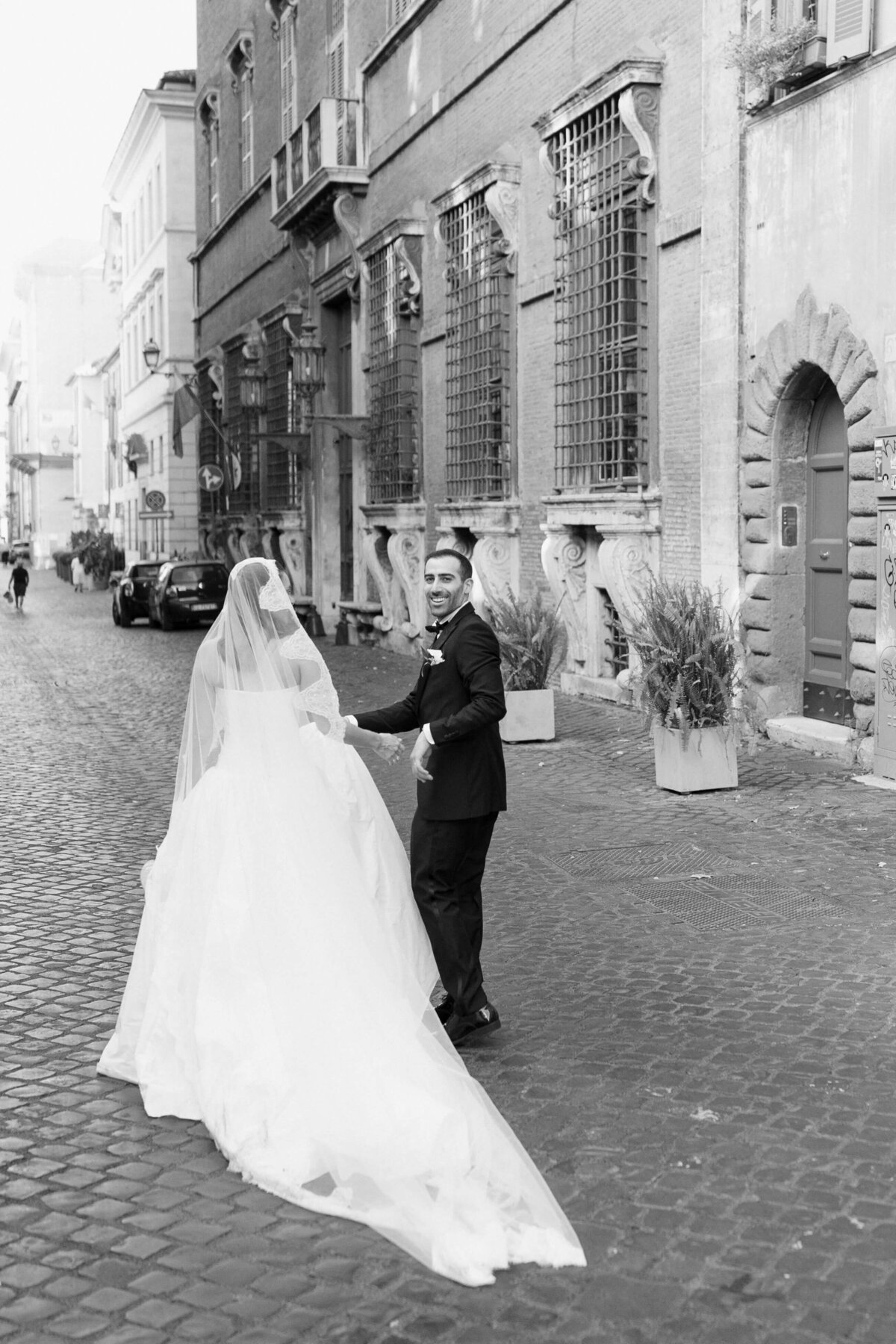 Groom twirling bride in romantic moment on Roman street

