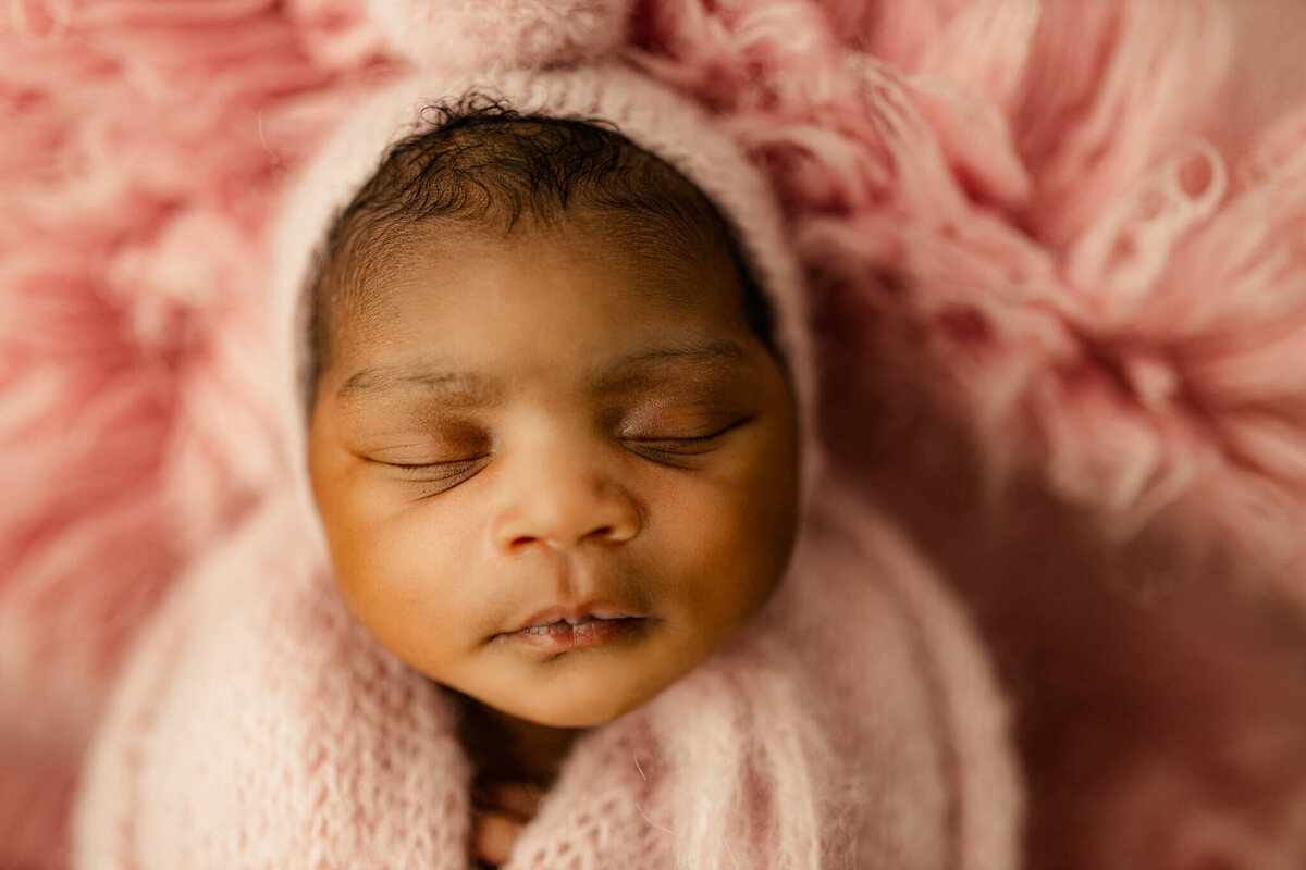 close up of baby swaddled on pink flotaki