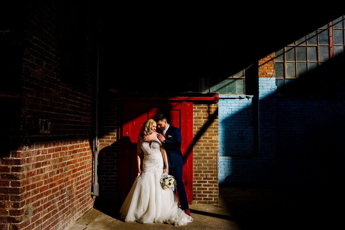bride and groom in front of red door at epic railyard venue In el paso texas