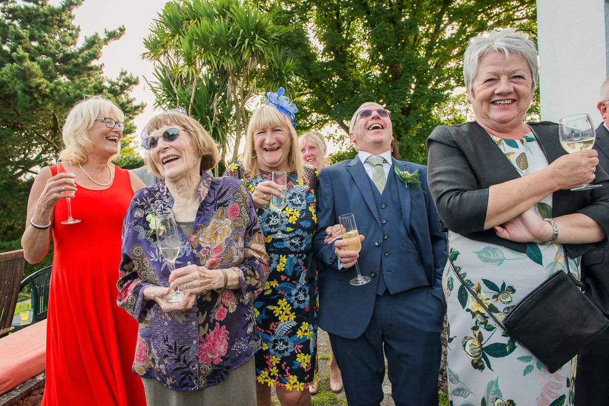 wedding guests standing on the terrace of Westcove House laughing at the wedding speeches