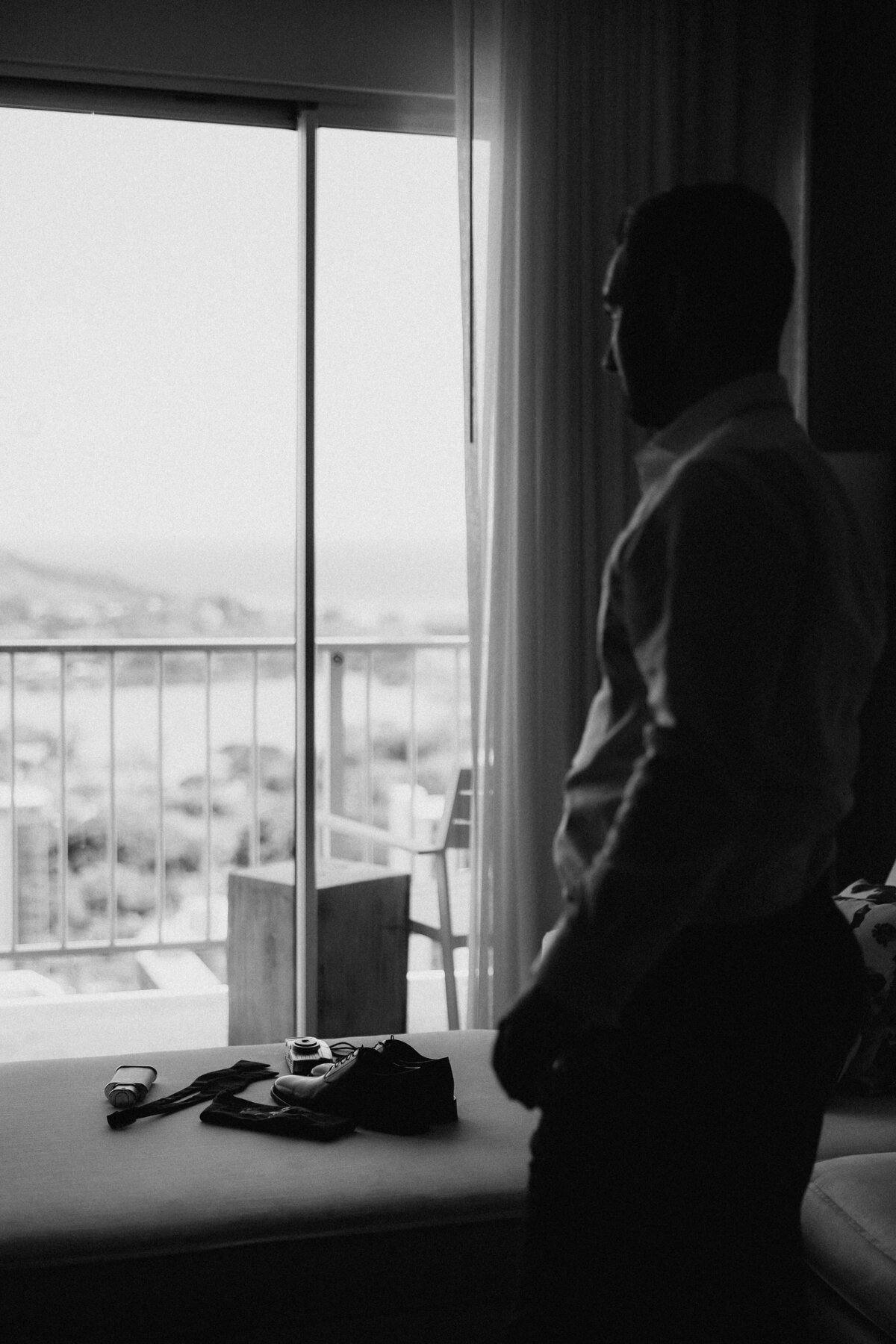 Hotel room in black and white with groom looking out the window