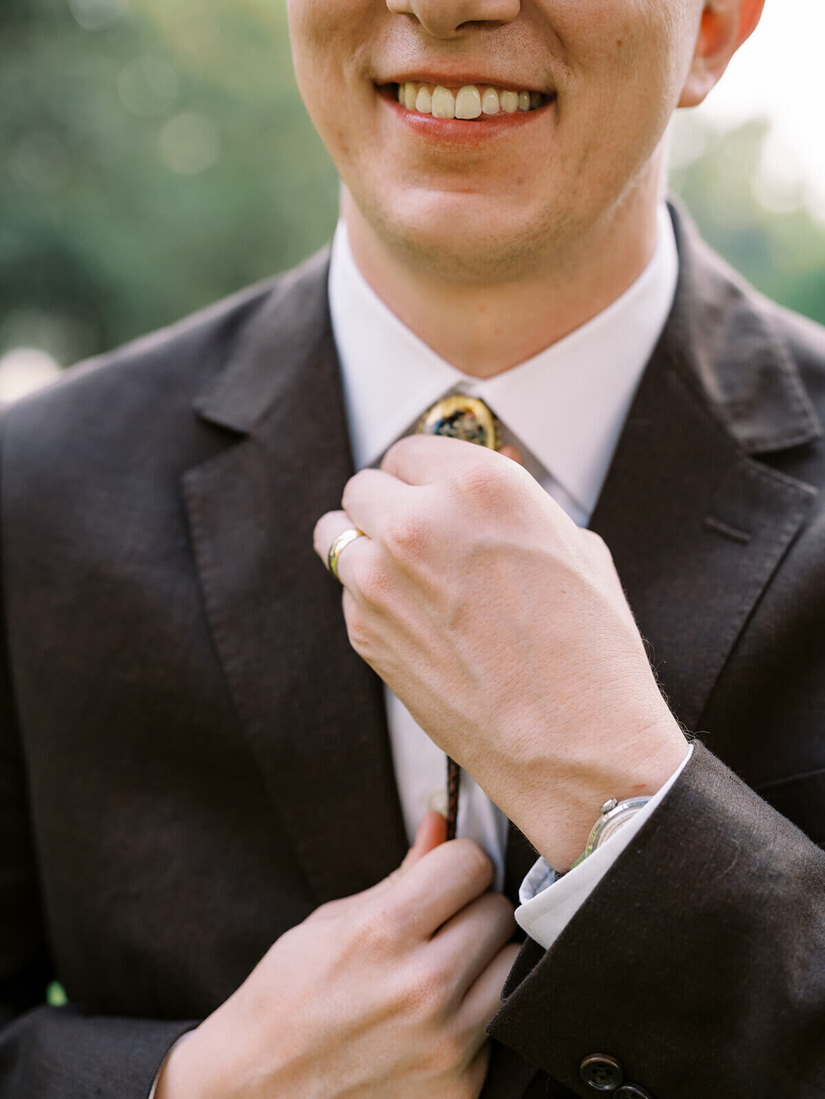 Close up of a faceless groom adjusting his tie. 