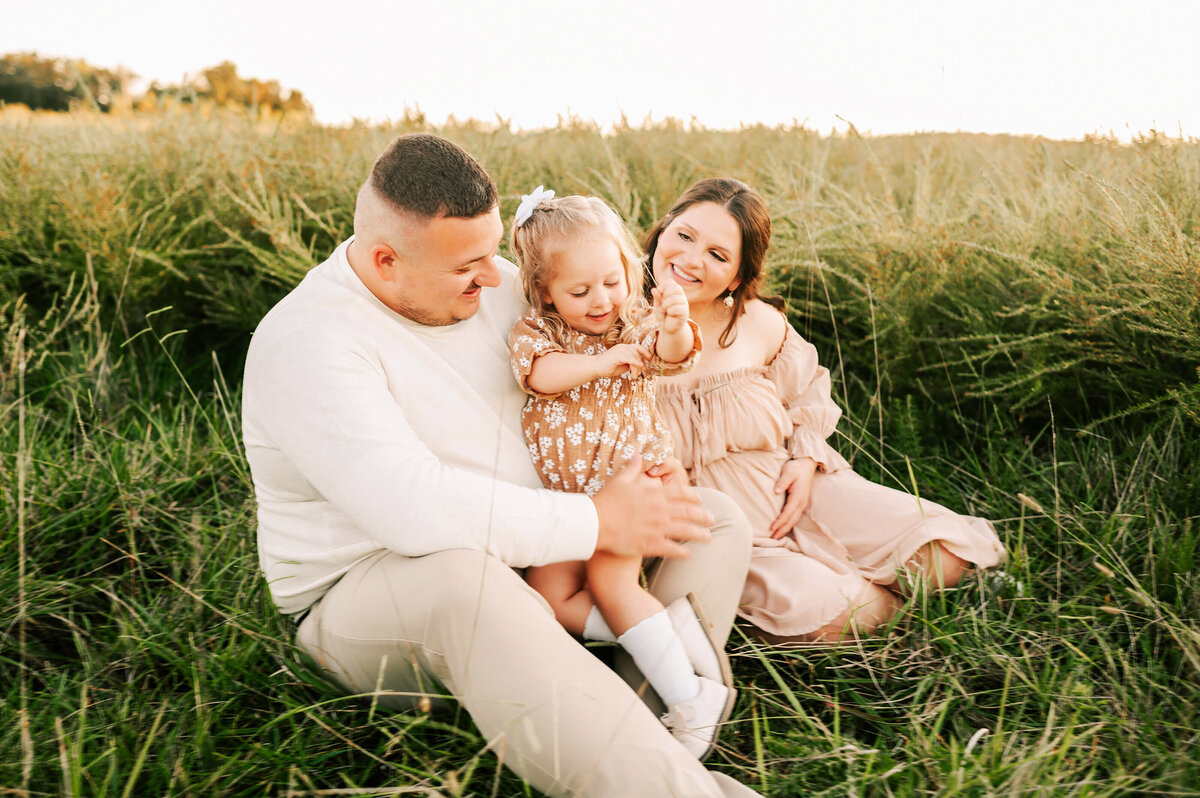 maternity photo in Springfield MO of pregnant couple playing with toddler in a field