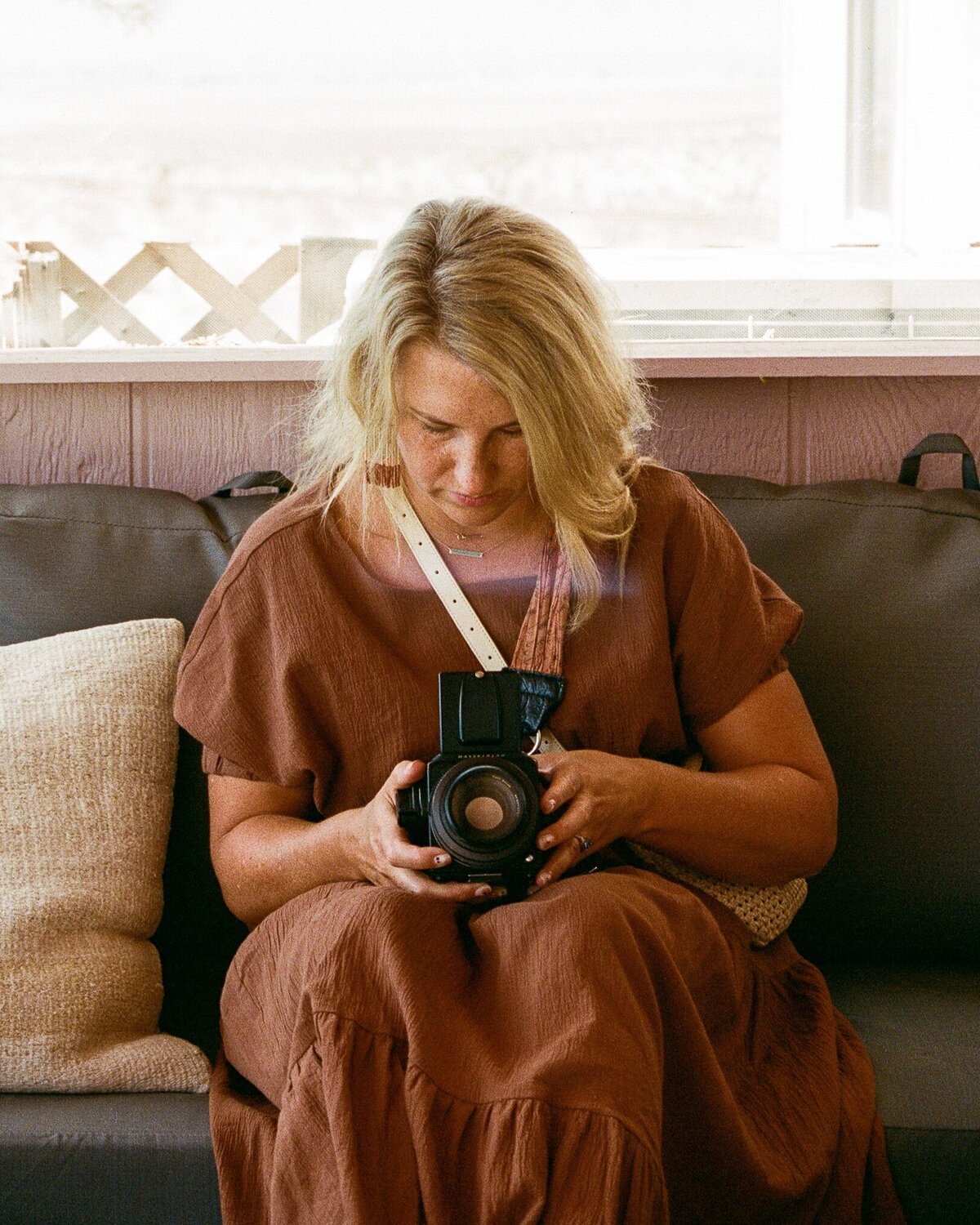 Woman looks at her camera while sitting on the couch