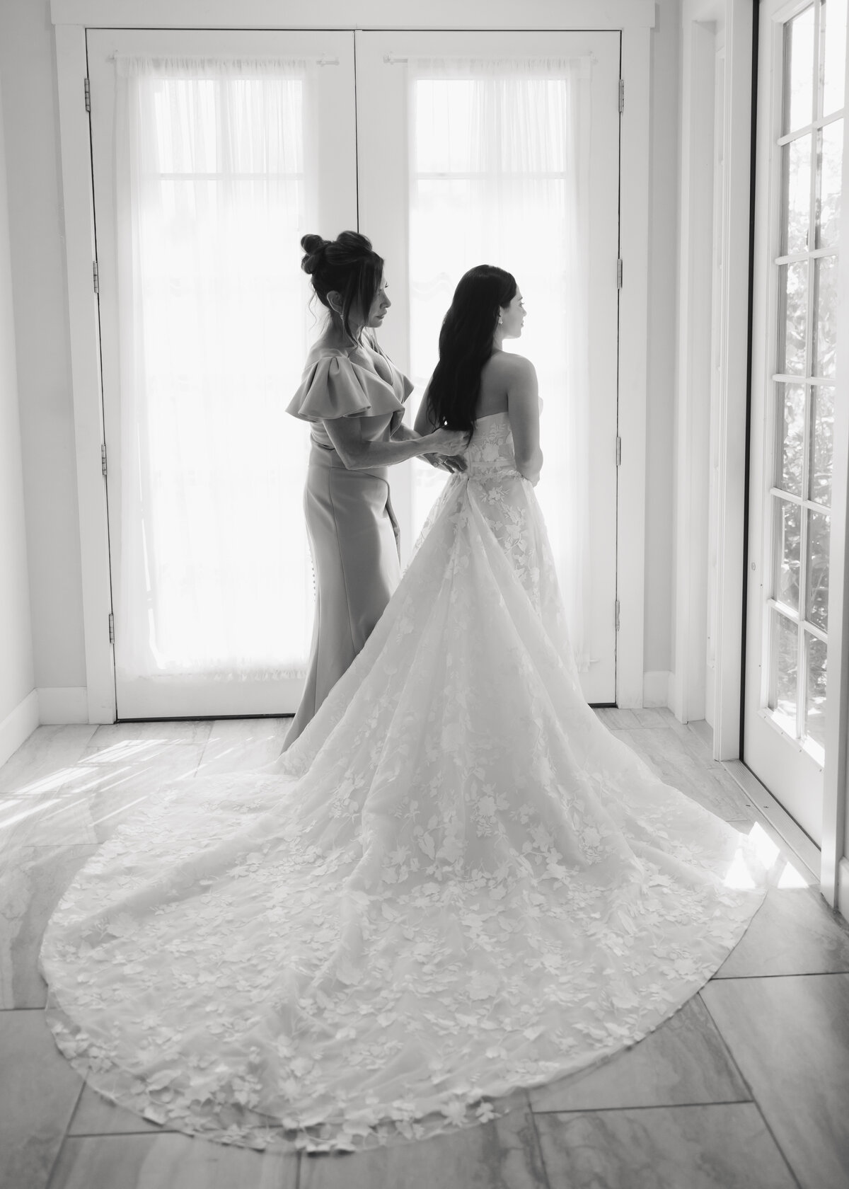 mother zips up brides wedding dress