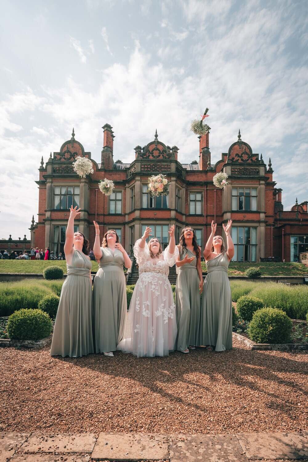 4 bridesmaids and bride throw flowers in the air in front of Welcombe Hotel