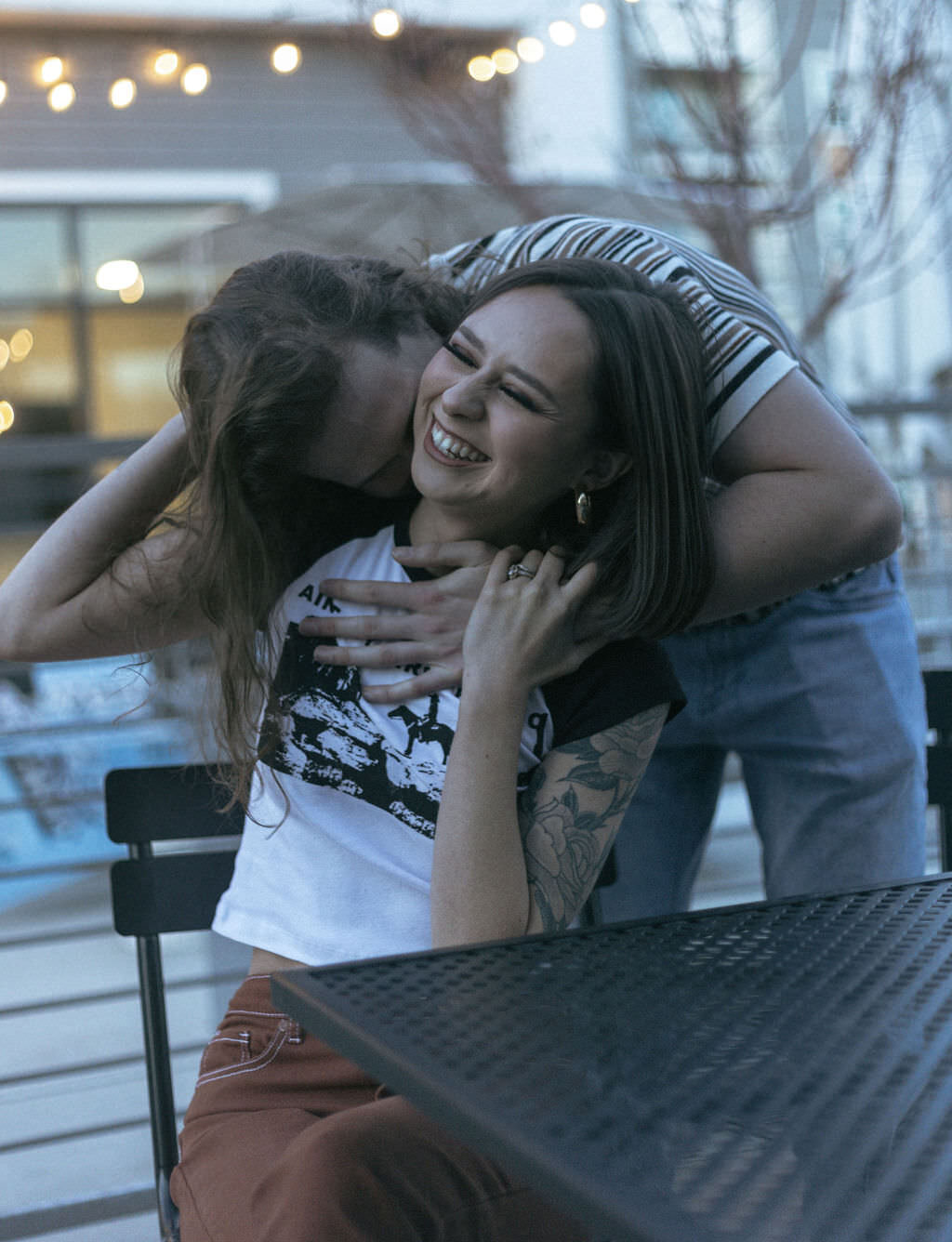 A person kissing their partner's neck as they are sitting in front of them.