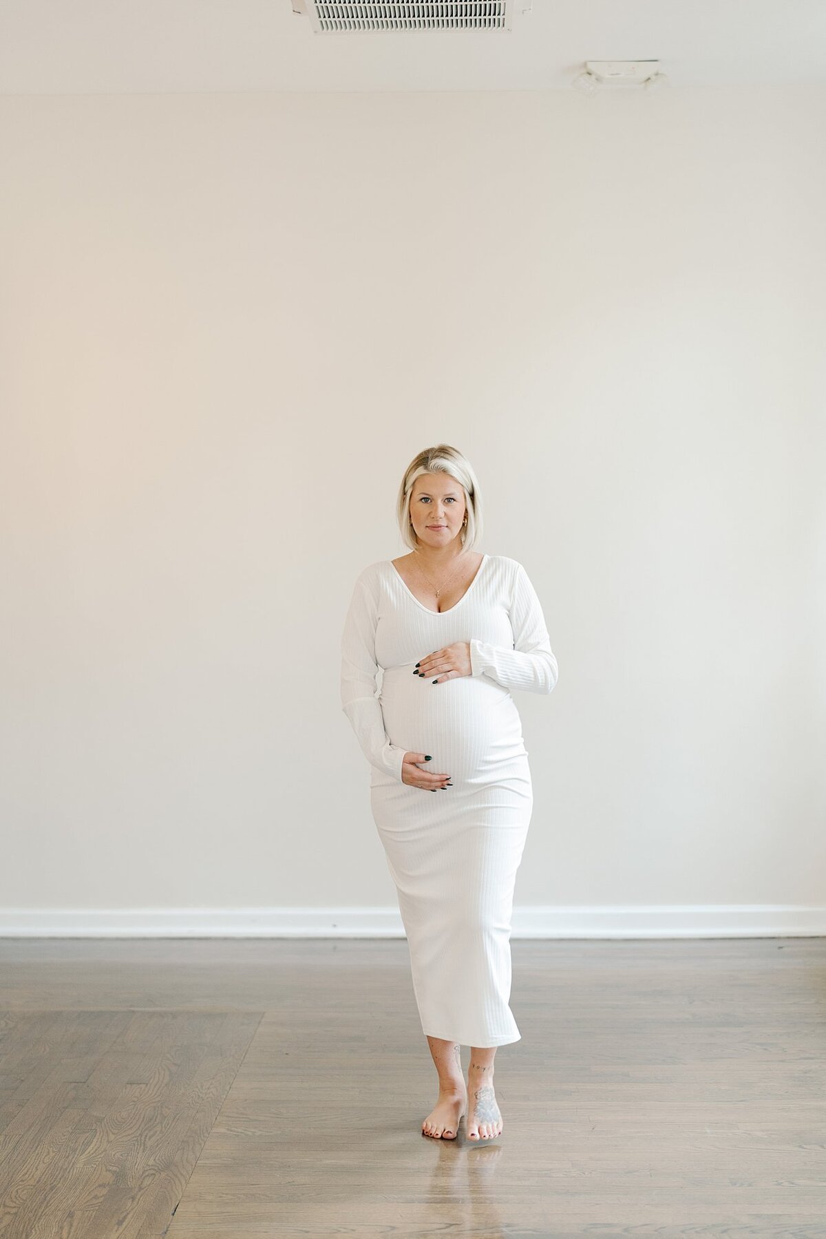 Pregnant woman in white dress in studio by Maternity Photographer Richmond VA