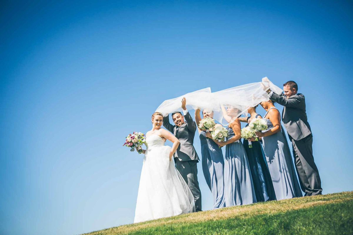 bridal party in blue dresses under bride's vail