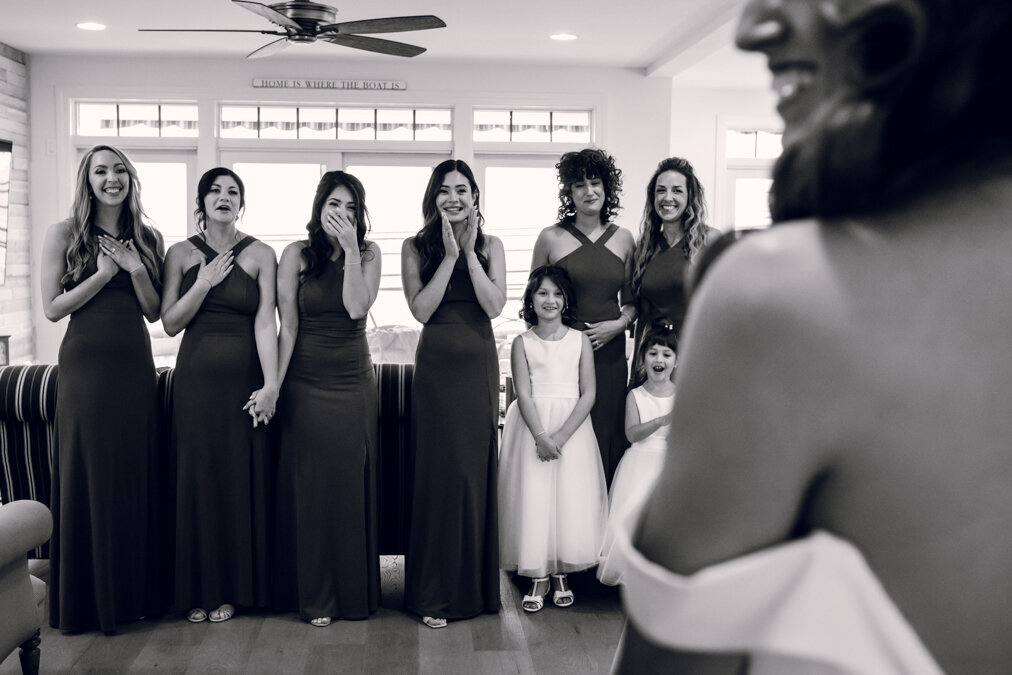A bride and her bridesmaids look at each other.