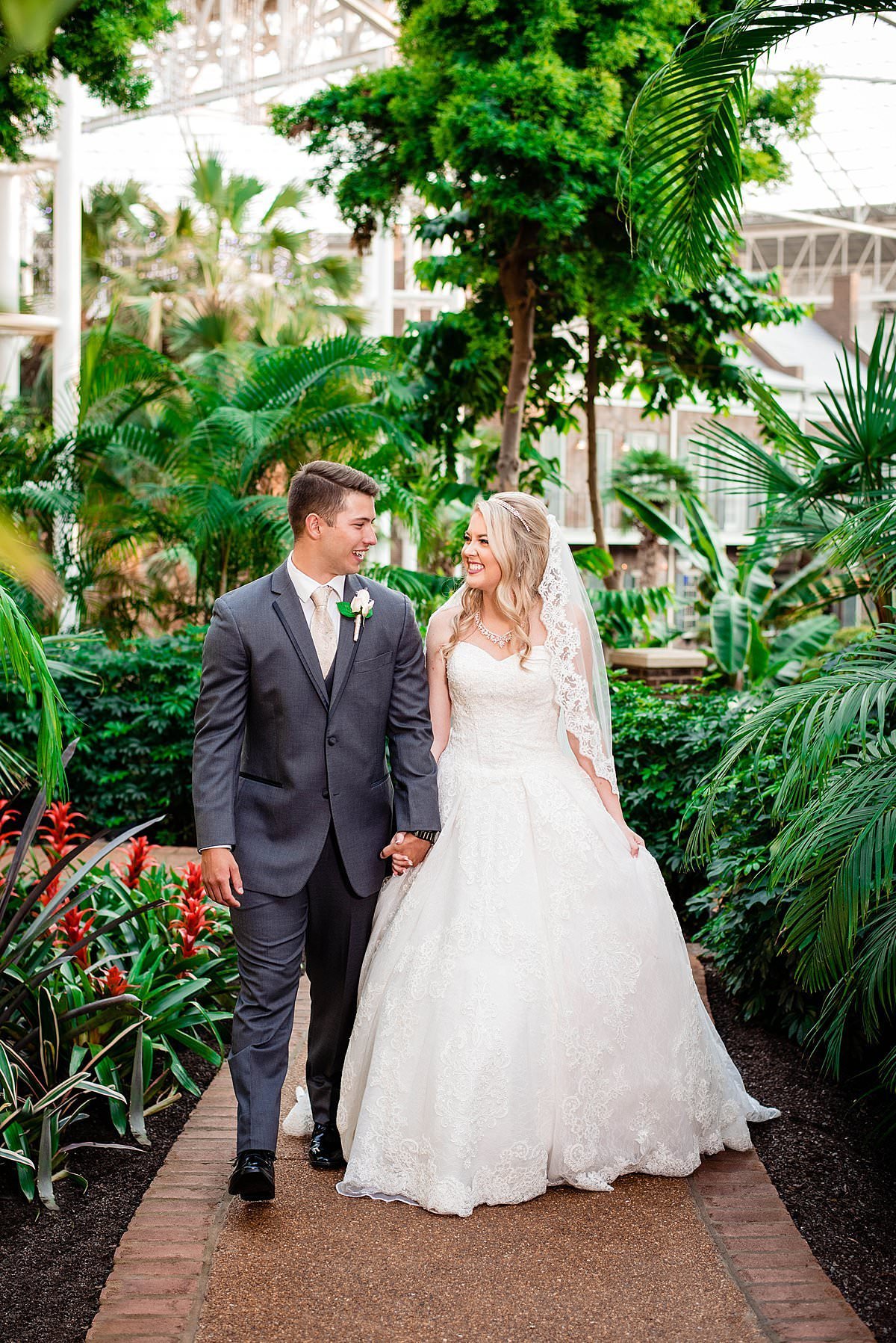 Newlywed couple walking hand in hand with palm trees behind