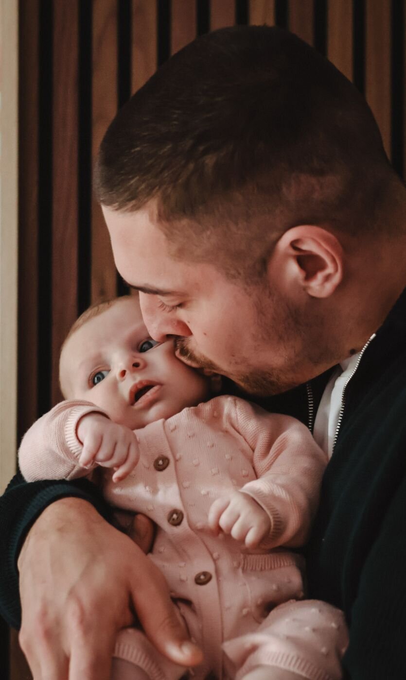 Een ontroerend portret van een vader die zijn pasgeboren baby kust, waarbij de nadruk ligt op hun intieme verbinding.