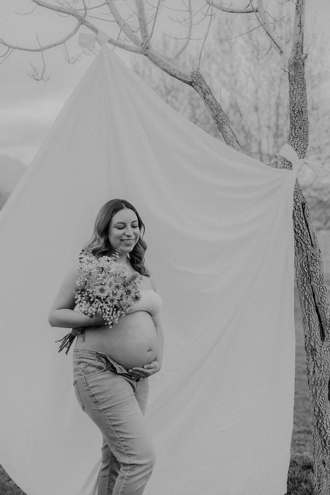 A woman looks down while holding her pregnant belly