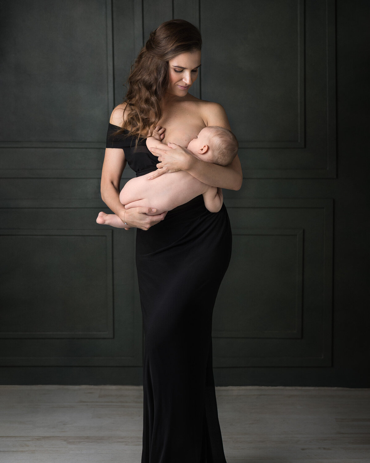 A mother breastfeeding her baby dressed in gorgeous black dress