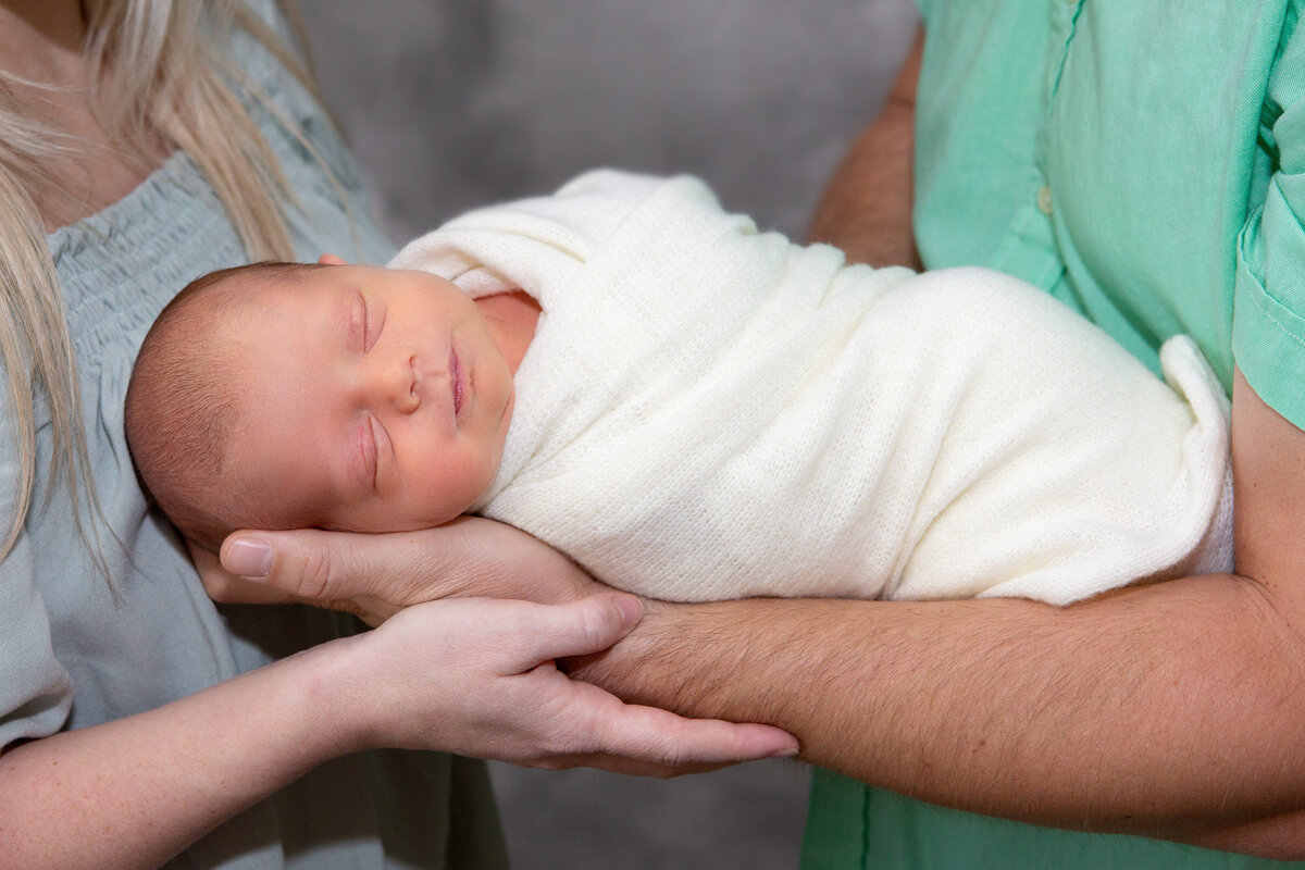 Cute newborn boy in his parent's arms with Ron Schroll Photography in Charlotte, NC
