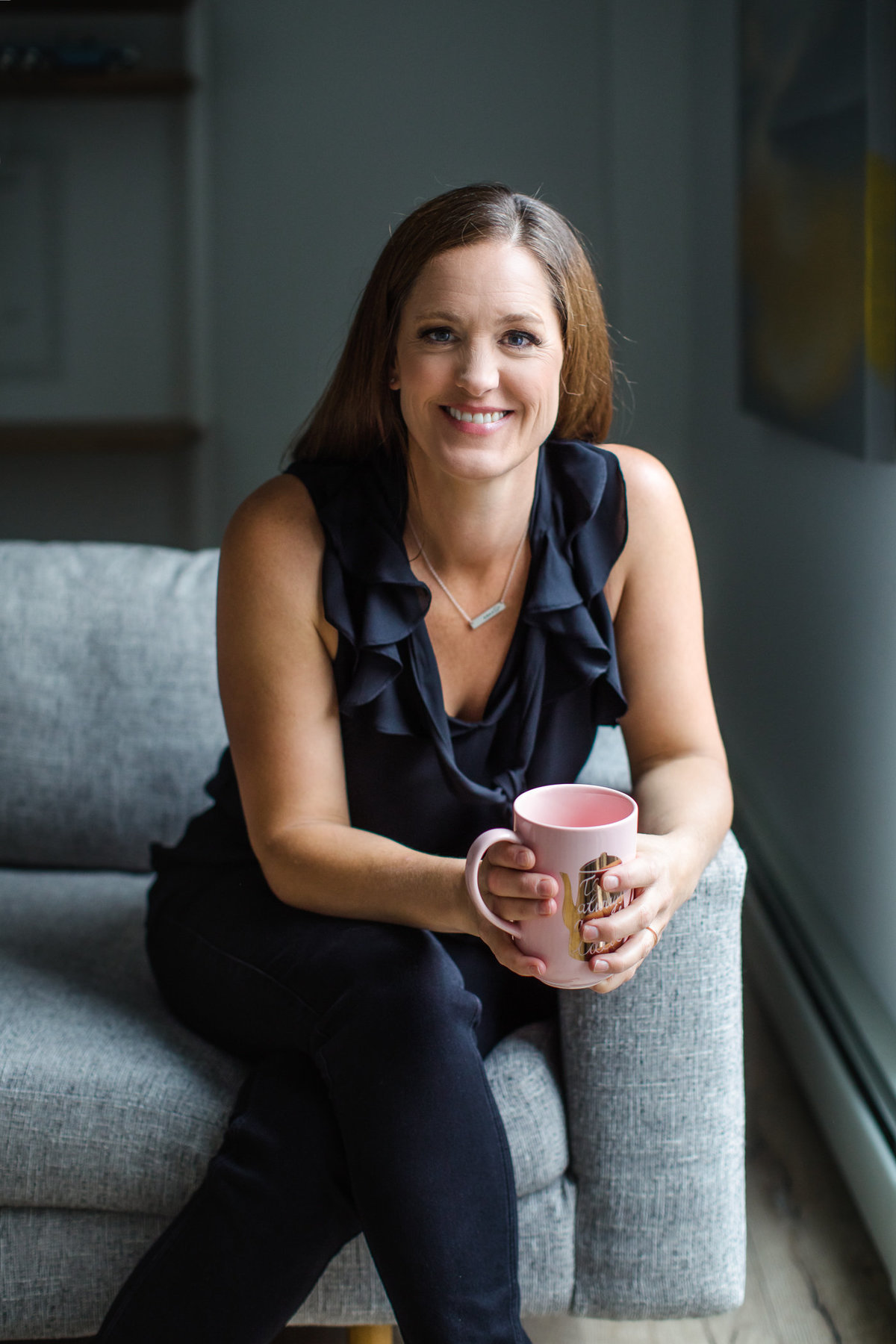 Portrait of woman smiling on a couch with coffee cup