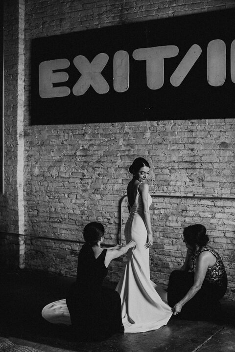 bride getting ready putting on her dress with her mother