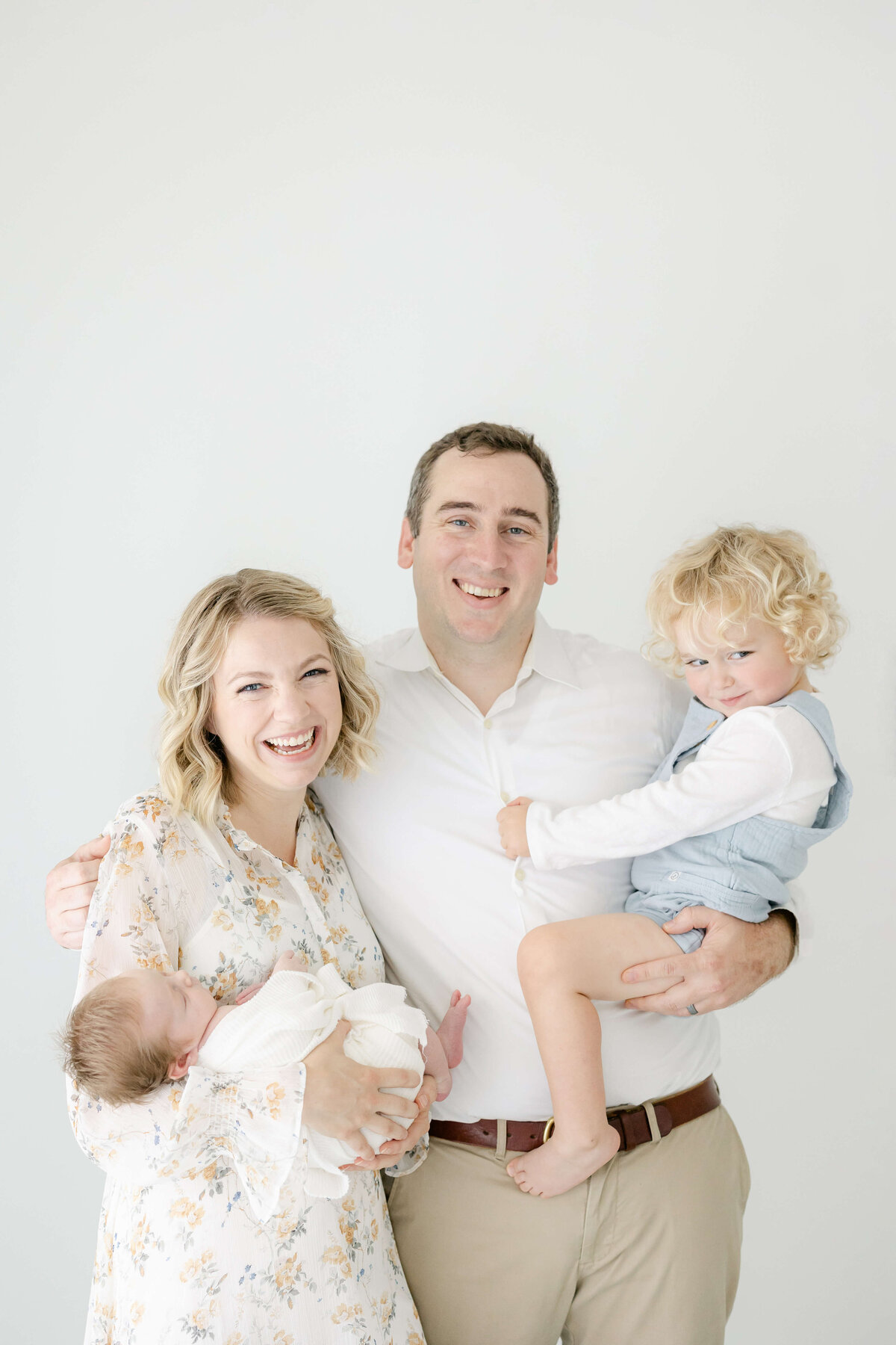 parents smiling with their newborn and toddler