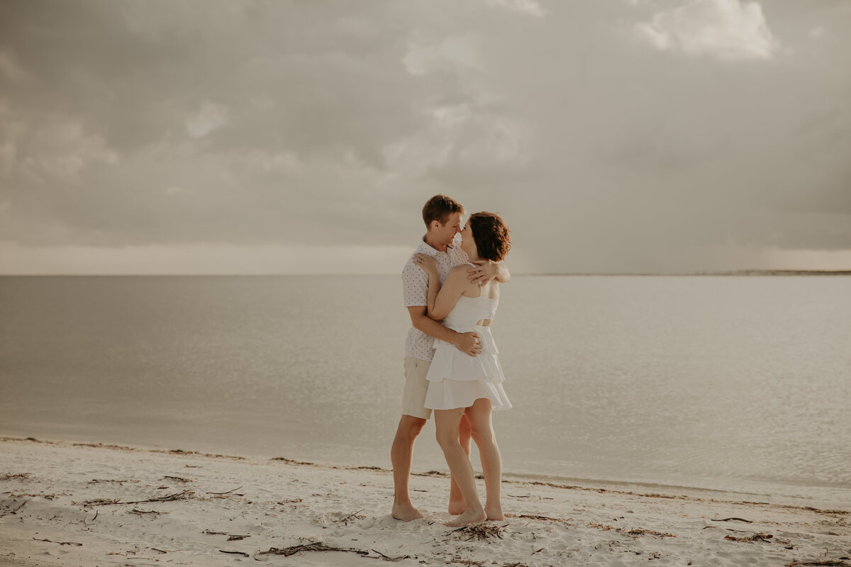 This image is of a couple kissing near the beach water.