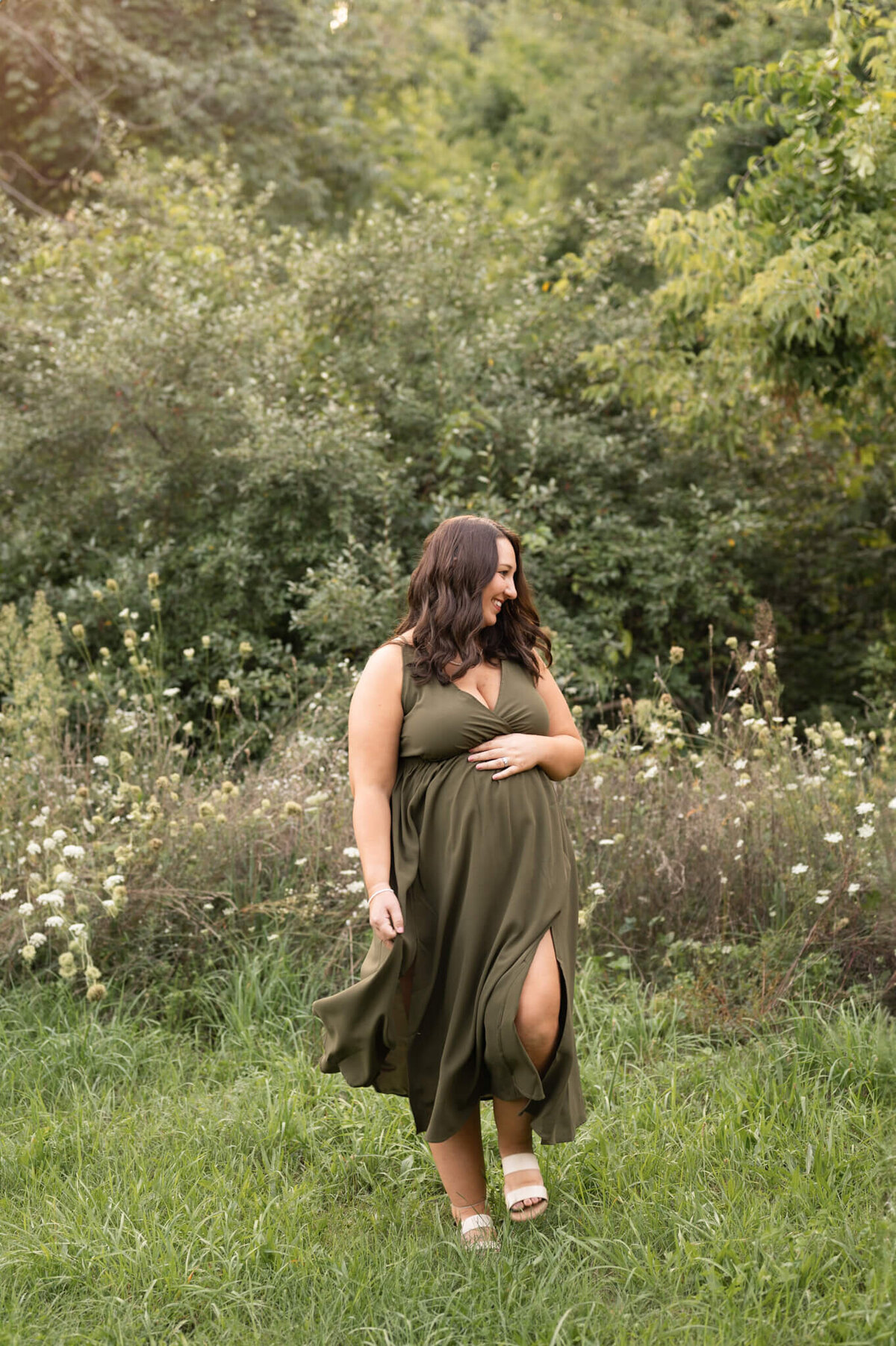 Pregnant woman standing in a flower field with a flowy dress in White Lake