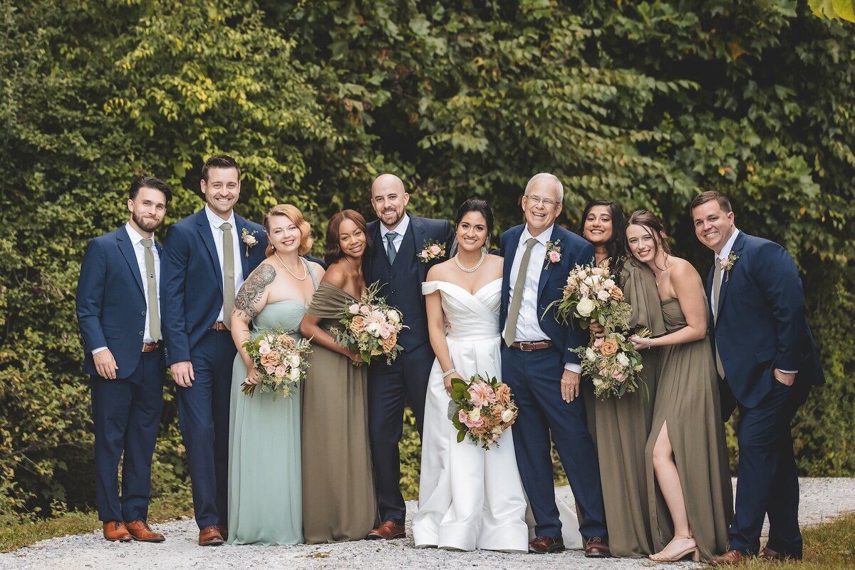 bride and groom smiling with wedding party