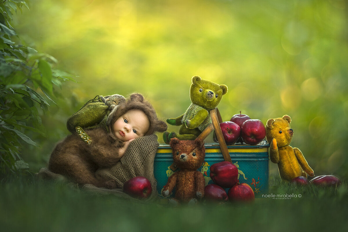 Newborn Baby resting on vintage antique picnic basket with apples and teddybears. Teddy bear's picnic.