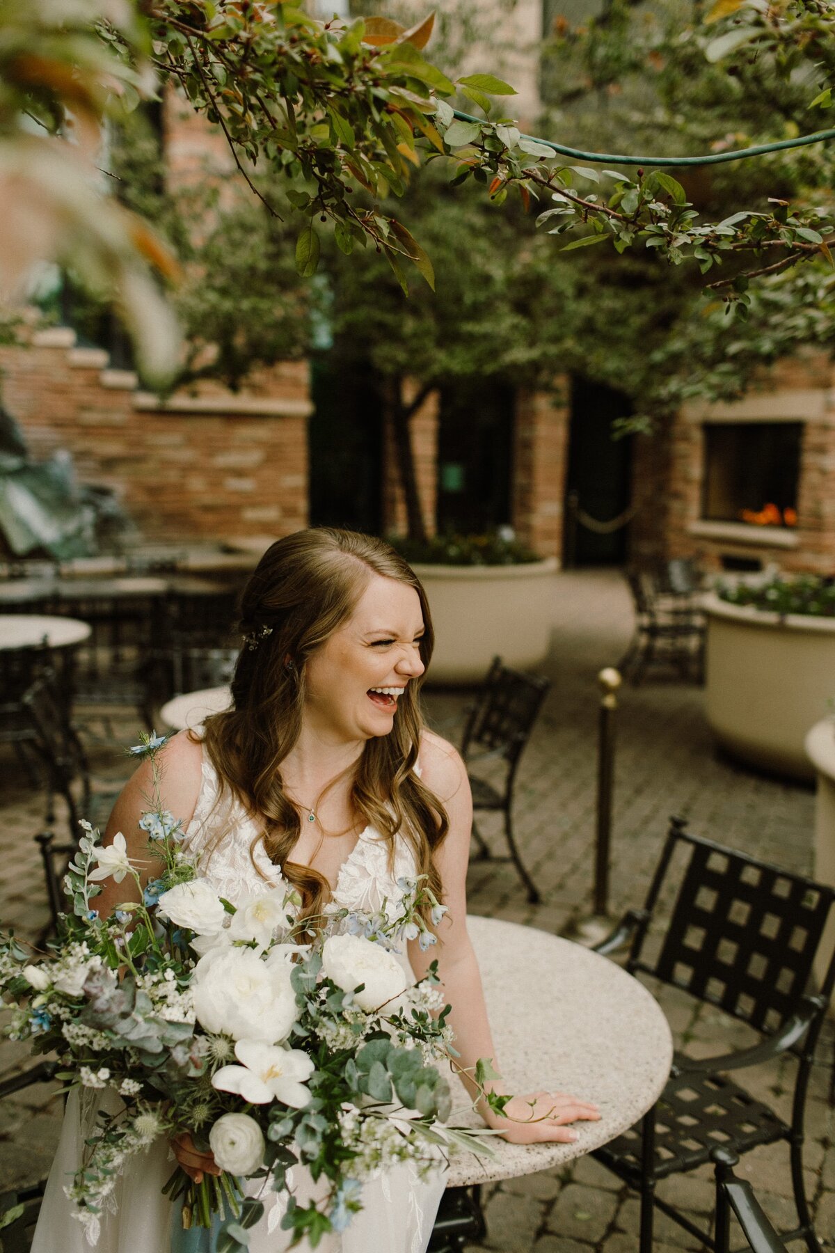 Bride smiles on her wedding day with her white and greenery bouquet at the St. Julien Hotel in Boulder Colorado.