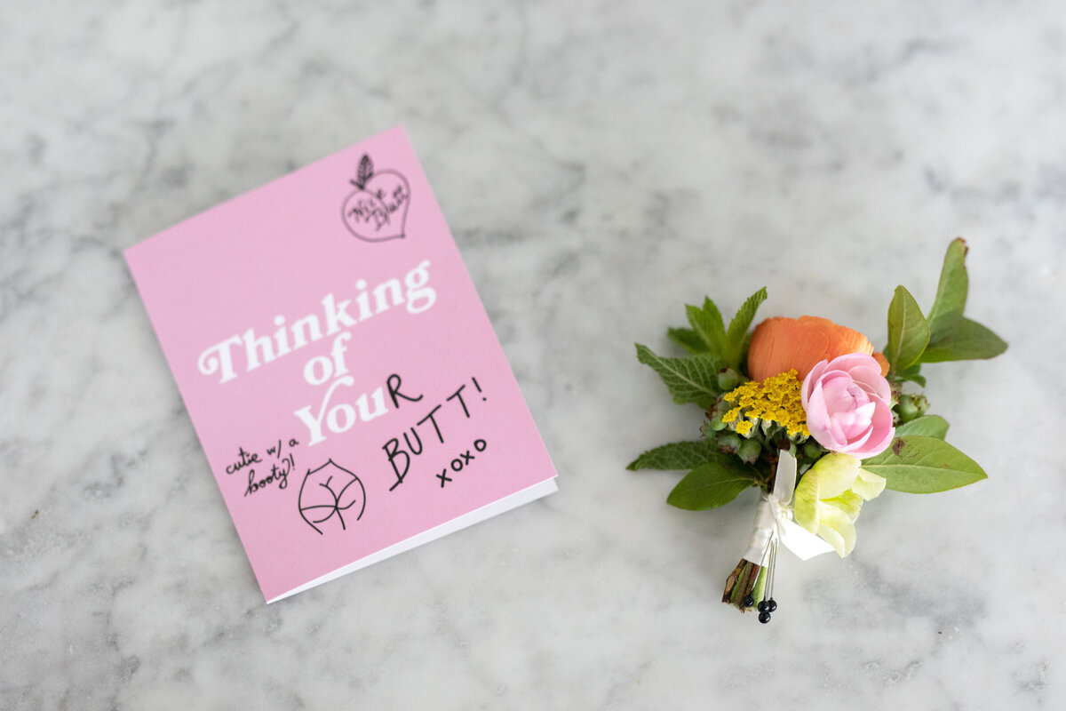 A card laying next to a small boutonniere.