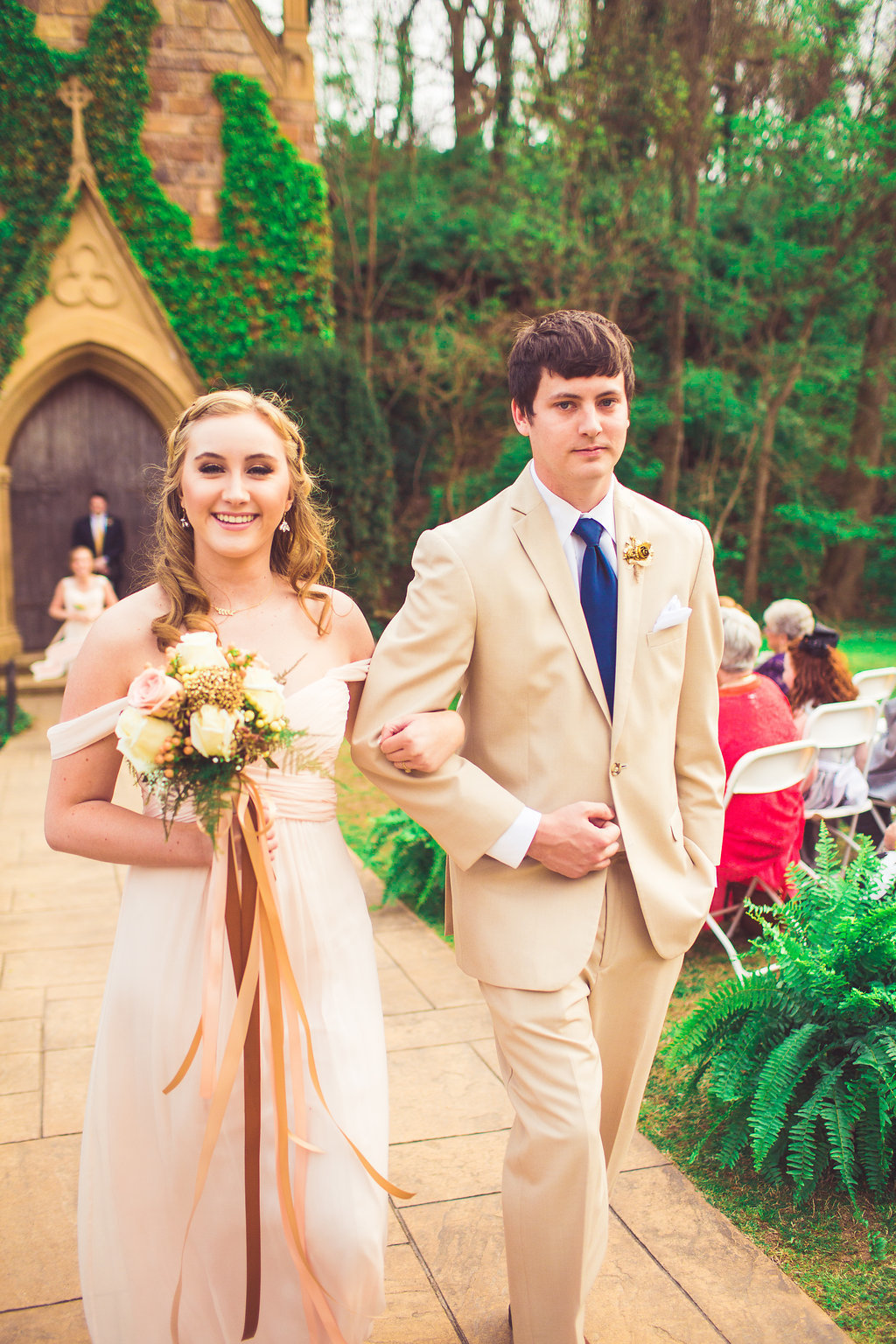 Wedding Photograph Of Bridesmaid in Peach Dress Holding a Bouquet and Groomsman in Light Brown Suit Walking Down The Aisle Los Angeles