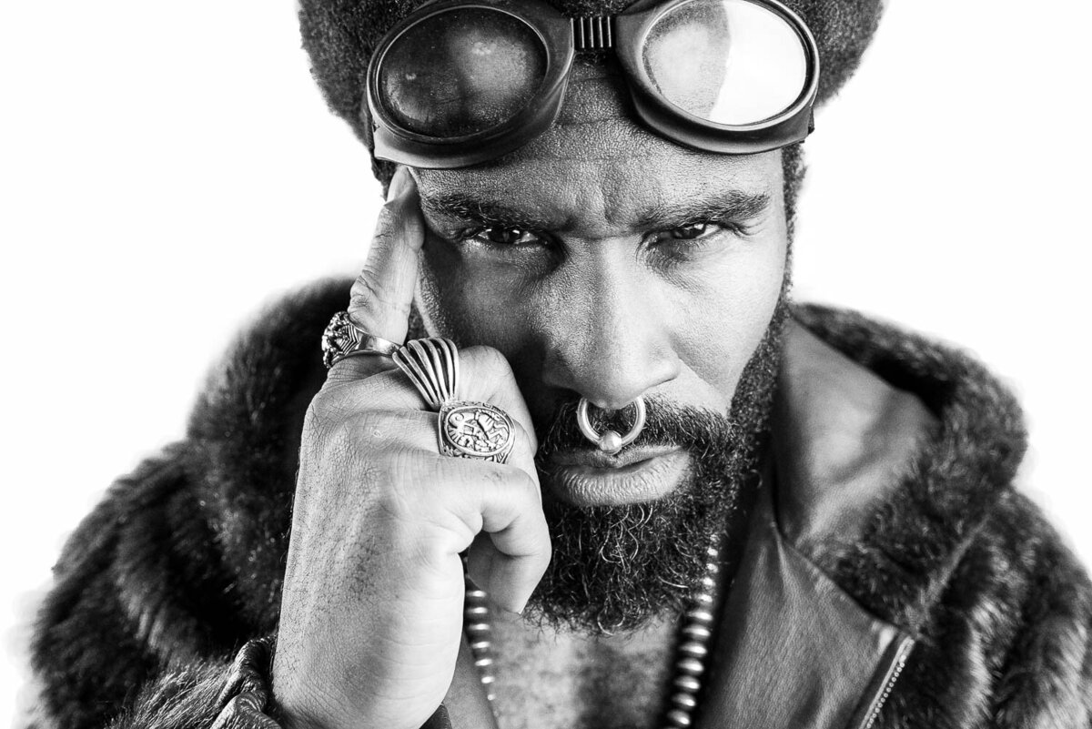 Editorial branding portrait of a person in styled cosplay attire with accessories and dramatic expression.