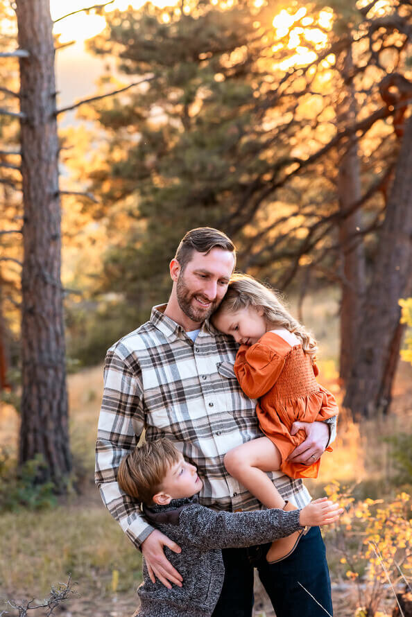 A dad hugs both his kids at a park in Colorado.