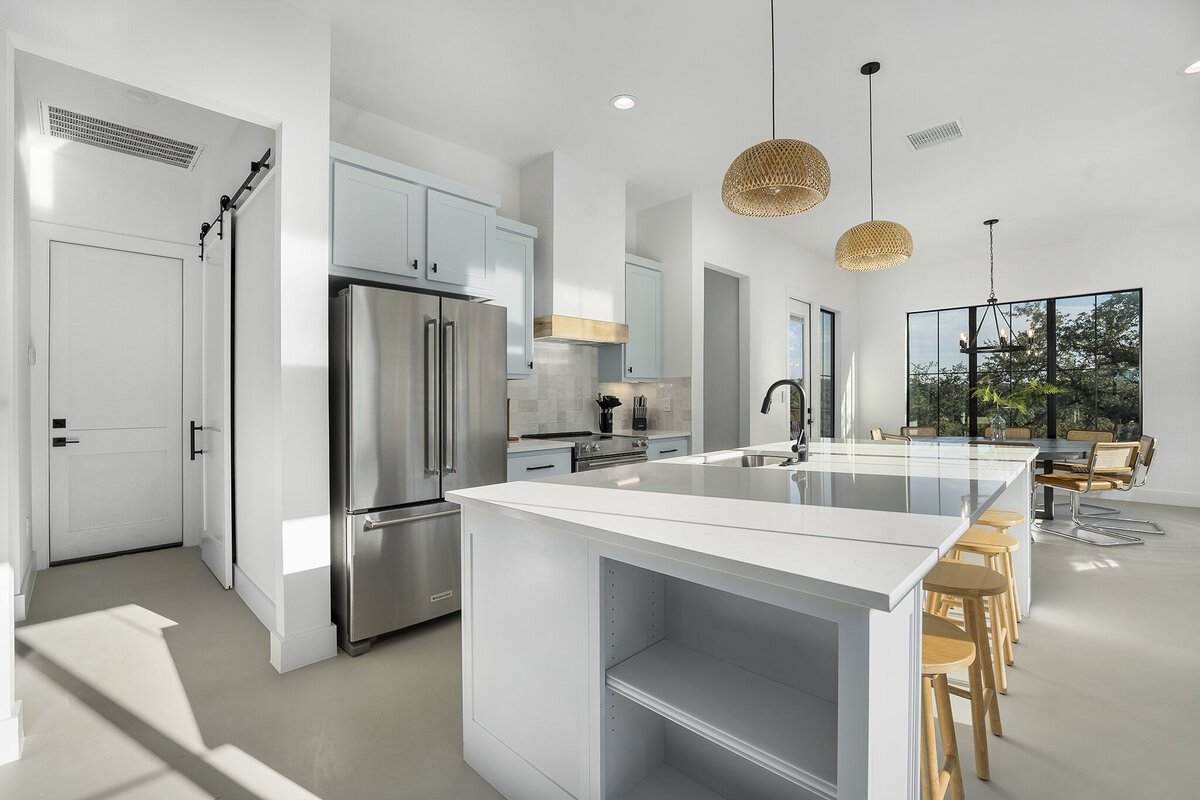 white kitchen island with woven rattan pendant lights