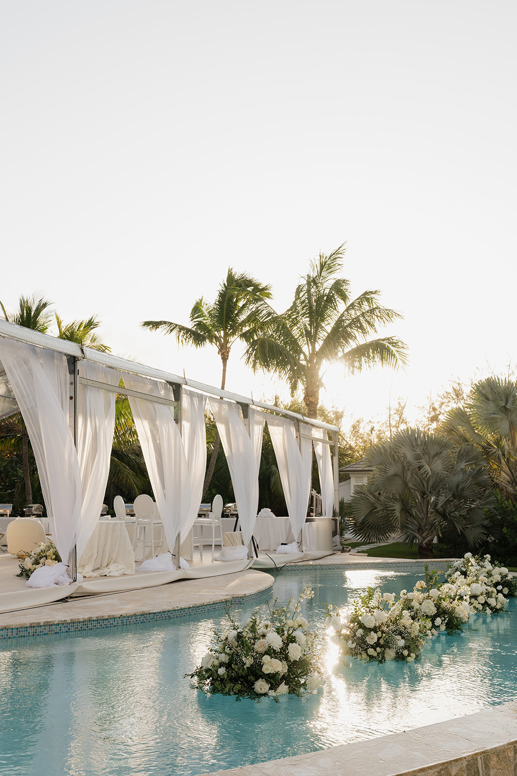 Floating pool floral arrangement for beach wedding in Eleuthera, Bahamas. Elegant wedding reception poolside with white and green floral design. Destination floral design by Rosemary & Finch Floral Design based in Nashville, TN.