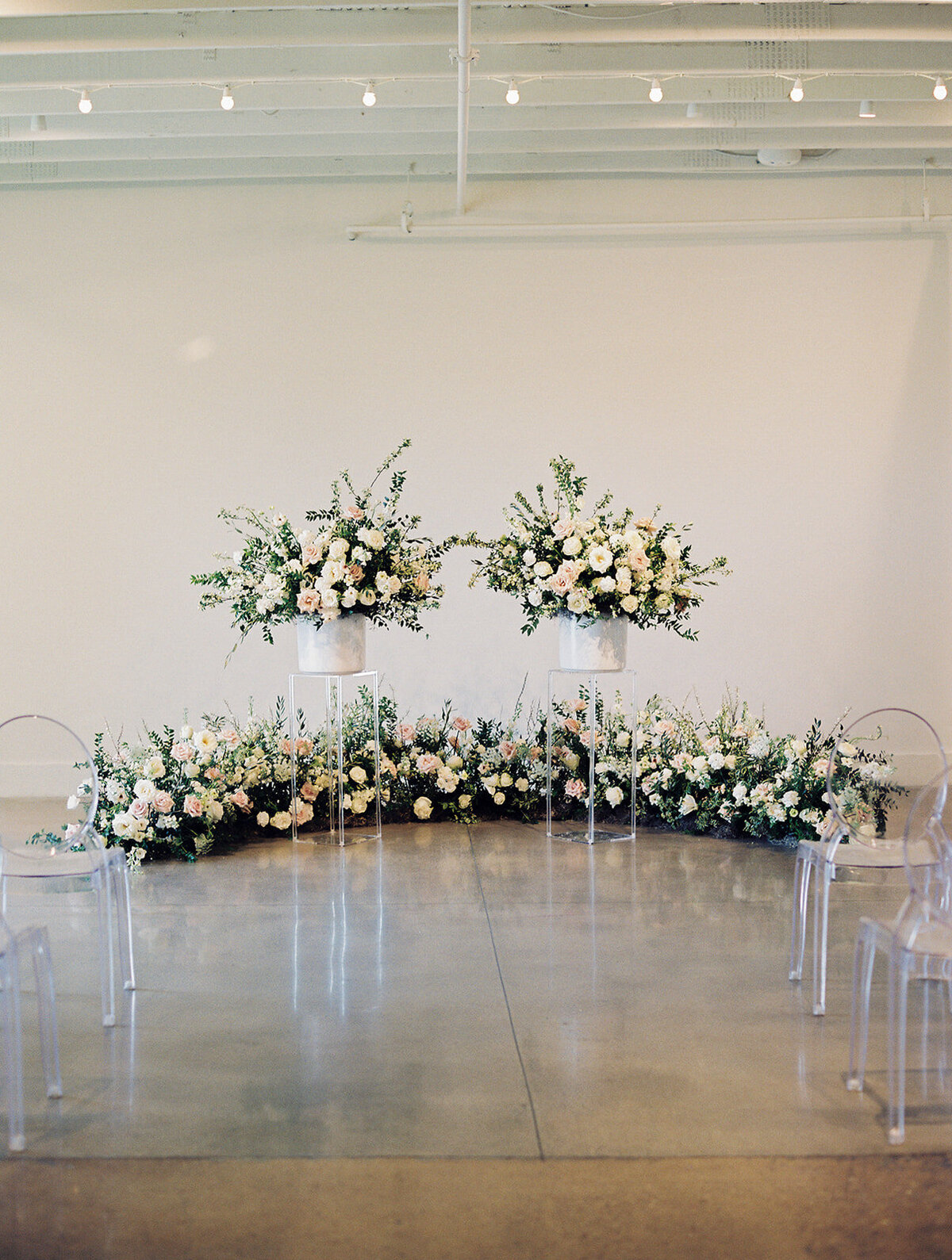 Lush ceremony installation featuring garden urns and meadows with petal heavy roses butterfly ranunculus, delphinium, and Queen Anne’s lace with natural, untamed greenery. Floral hues of white, cream, and blush. Designed by Rosemary and Finch in Nash