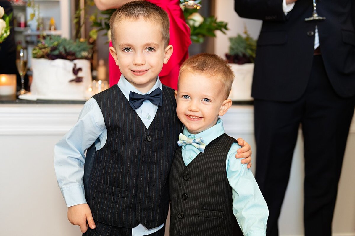 Two little boys in vests and bowties at wedding posing for the camera