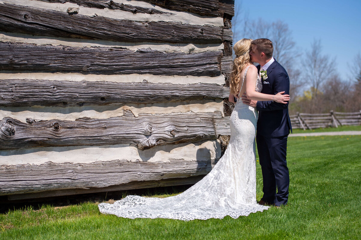 A bride and groom kiss for their Ottawa wedding photos outside the barns at Stonefields Estate wedding venue