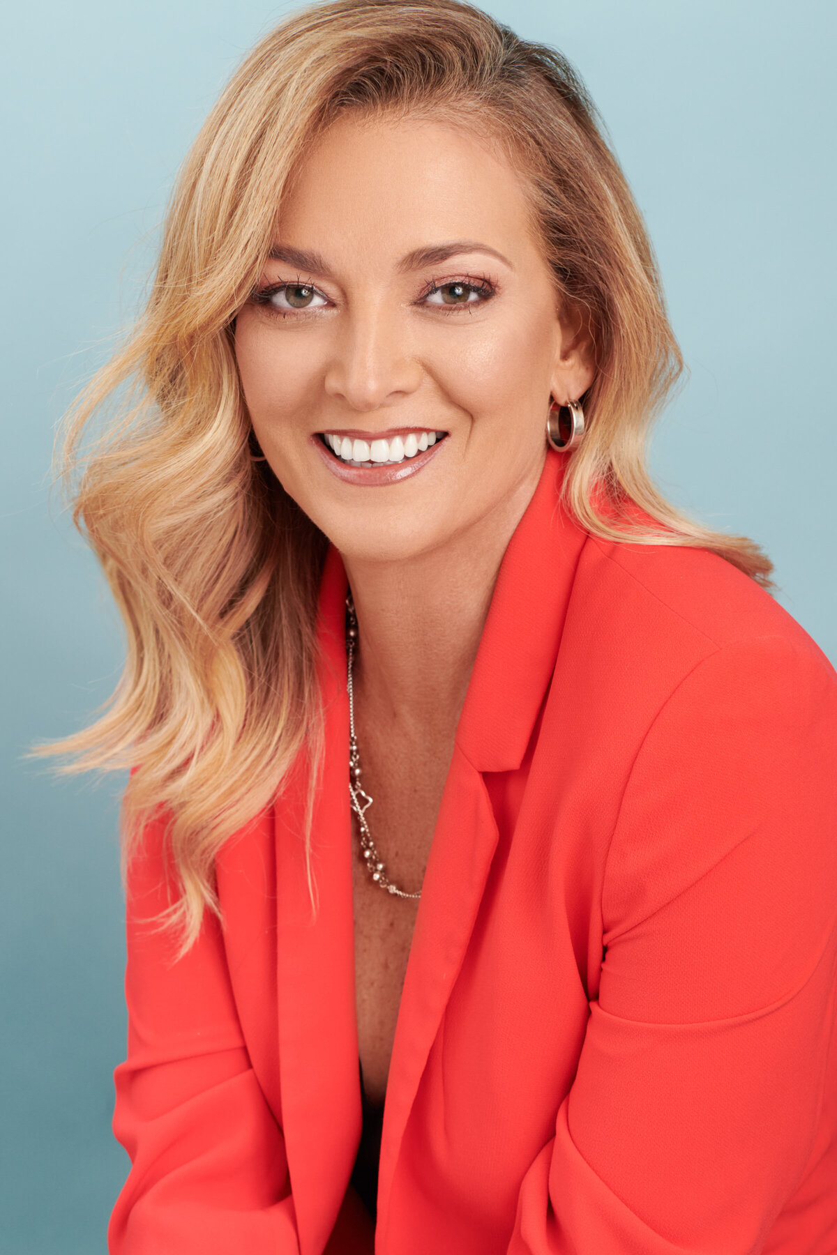 Beautiful woman in Coral jacket smiling for headshot