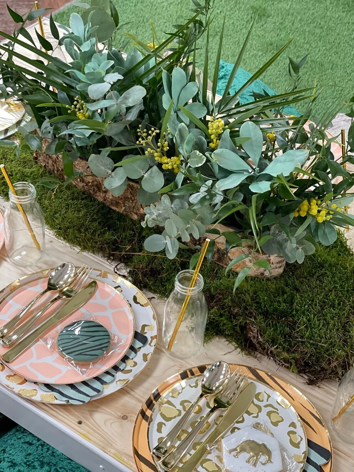 Jungle themed table setting with jungle plates and iced biscuit favours with a long greenery arrangement